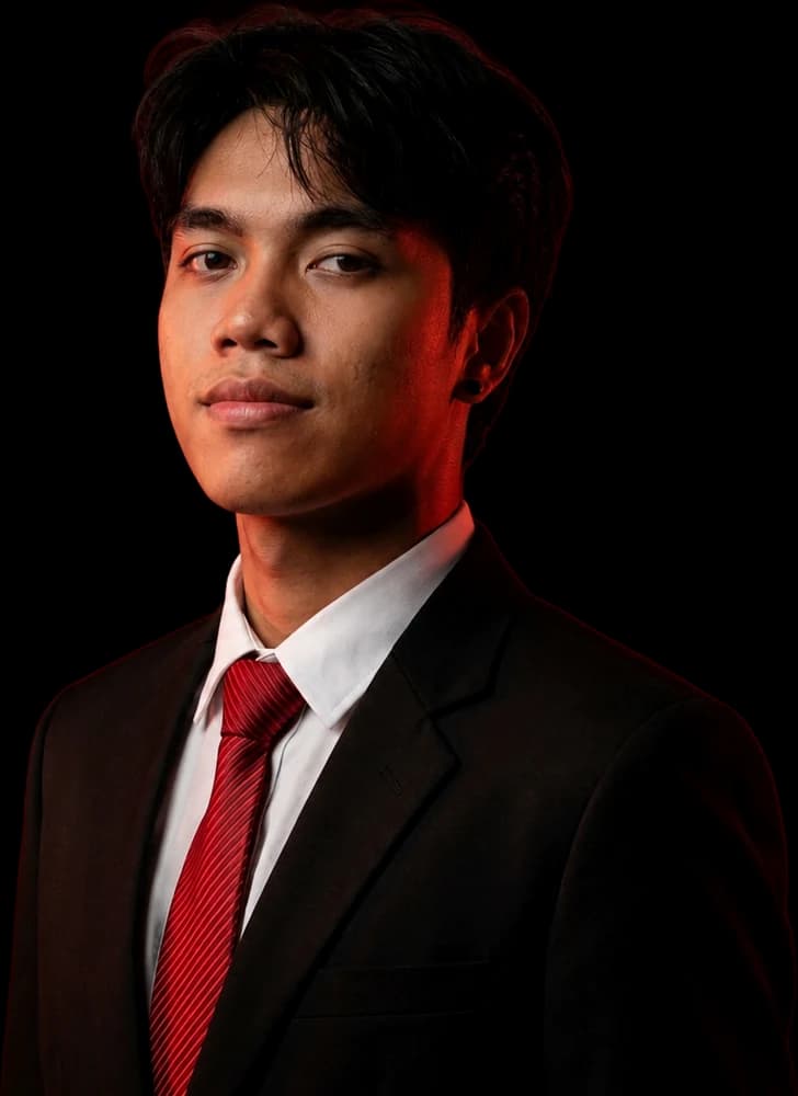 Portrait of Jhade in a black suit and red tie